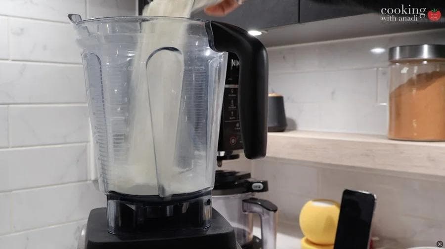 Blender filled with crepe batter being prepared on a kitchen counter.