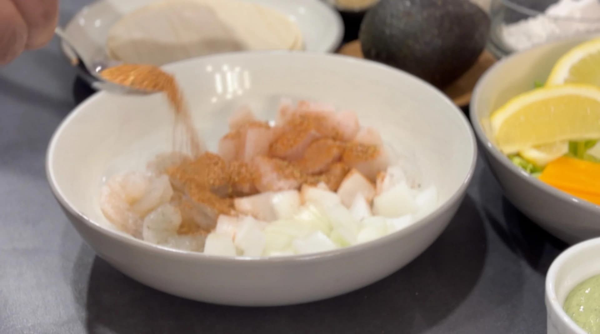 Marinated basa fish and shrimp with diced onions in a white bowl, ready for breading.