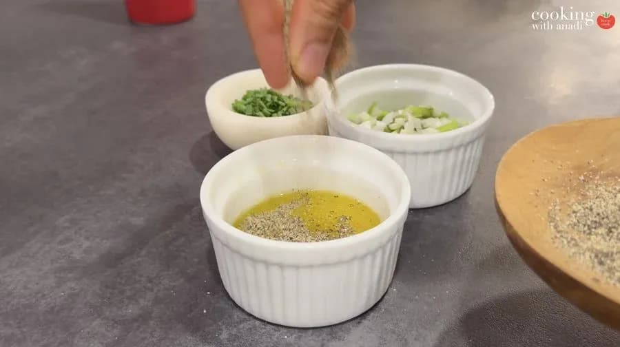 Mise en place with bowls of melted butter and oil mixture, chopped green onions, fresh herbs, and sesame seeds for air fryer potatoes recipe.