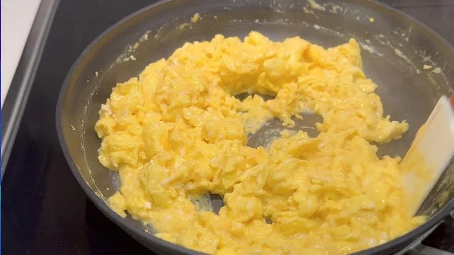 Scrambled eggs in a pan at the slightly runny stage, ready for breakfast burritos