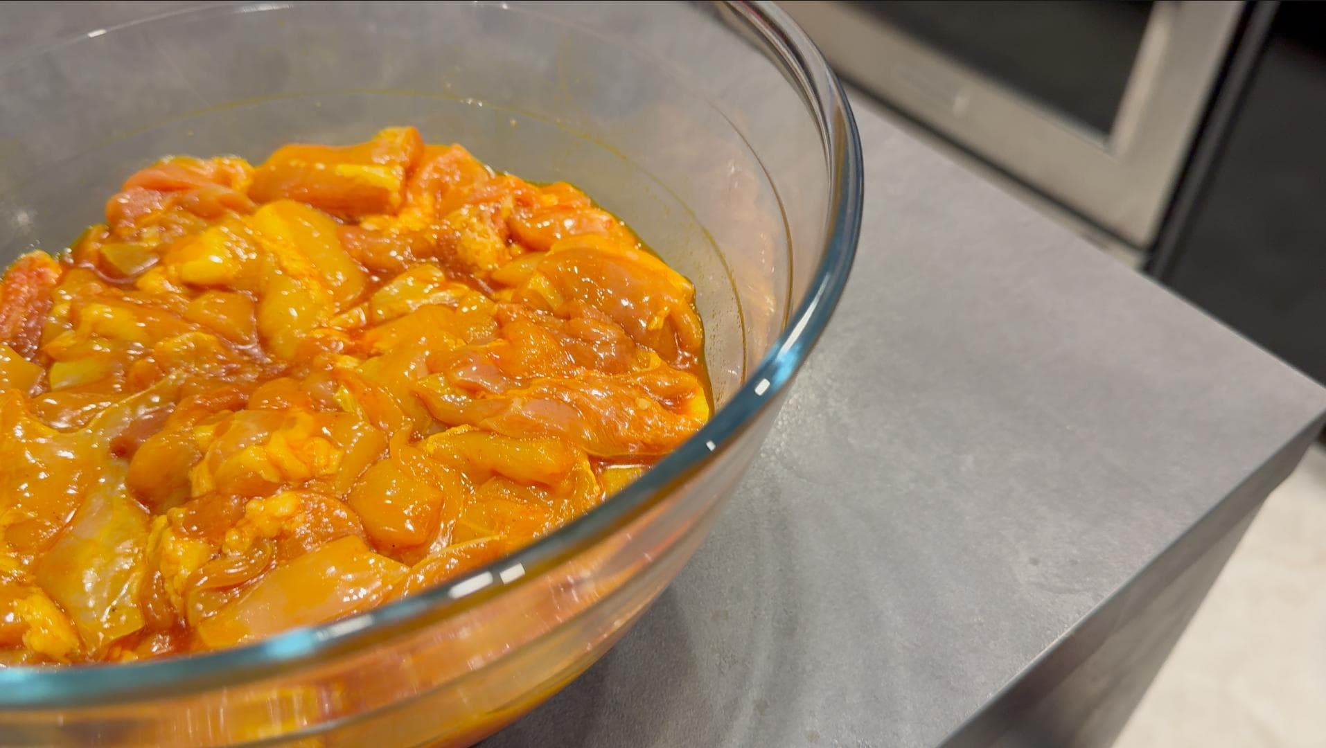 Saffron-infused marinade with chicken pieces in a glass bowl during first marinating stage.