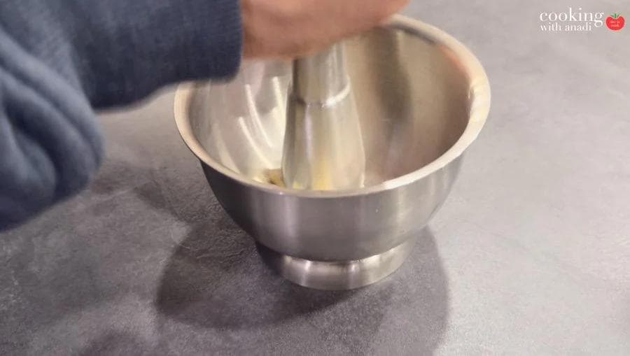 Whisking marinade ingredients together in a stainless steel mixing bowl on a gray surface.