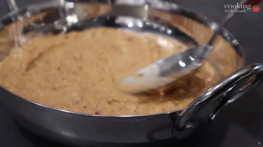 Smooth peanut chutney being blended in a pan with a spatula, showing creamy beige texture with spice specks.