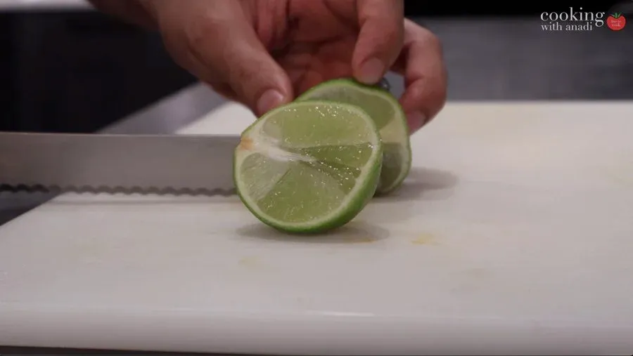 Slicing fresh lime into thin rounds on a white cutting board with a serrated knife