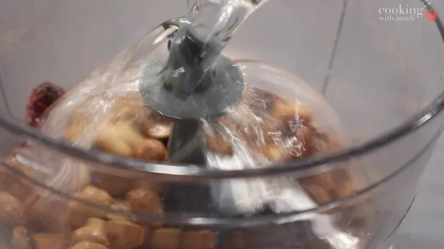Food processor blending roasted peanuts with spices and tamarind into smooth peanut chutney paste.