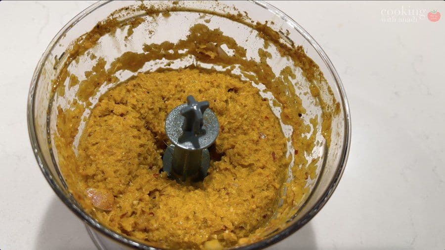Golden spice paste blended in a food processor with the blade visible in the center.