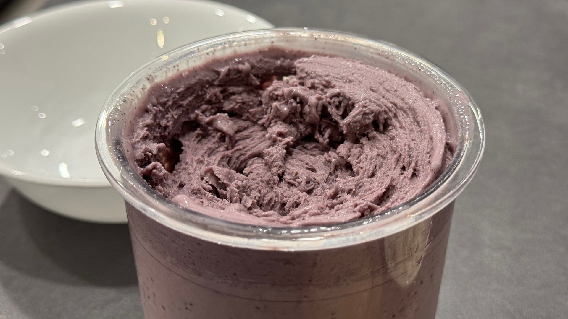Blueberry cheesecake protein ice cream in a clear container with a textured, frozen surface, ready to be served.