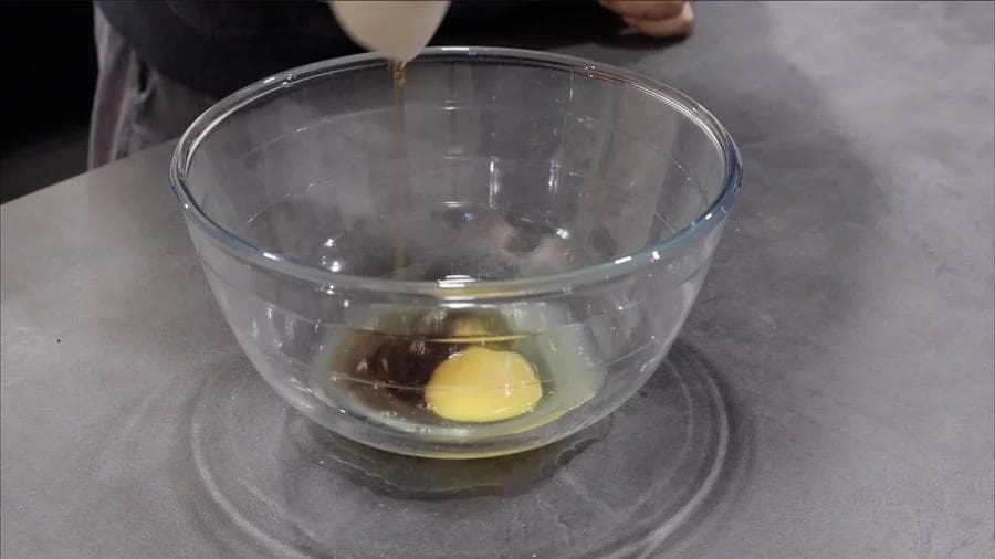 Wet ingredients for pumpkin cookies mixed in a glass bowl, including egg yolk and light-colored liquid mixture.
