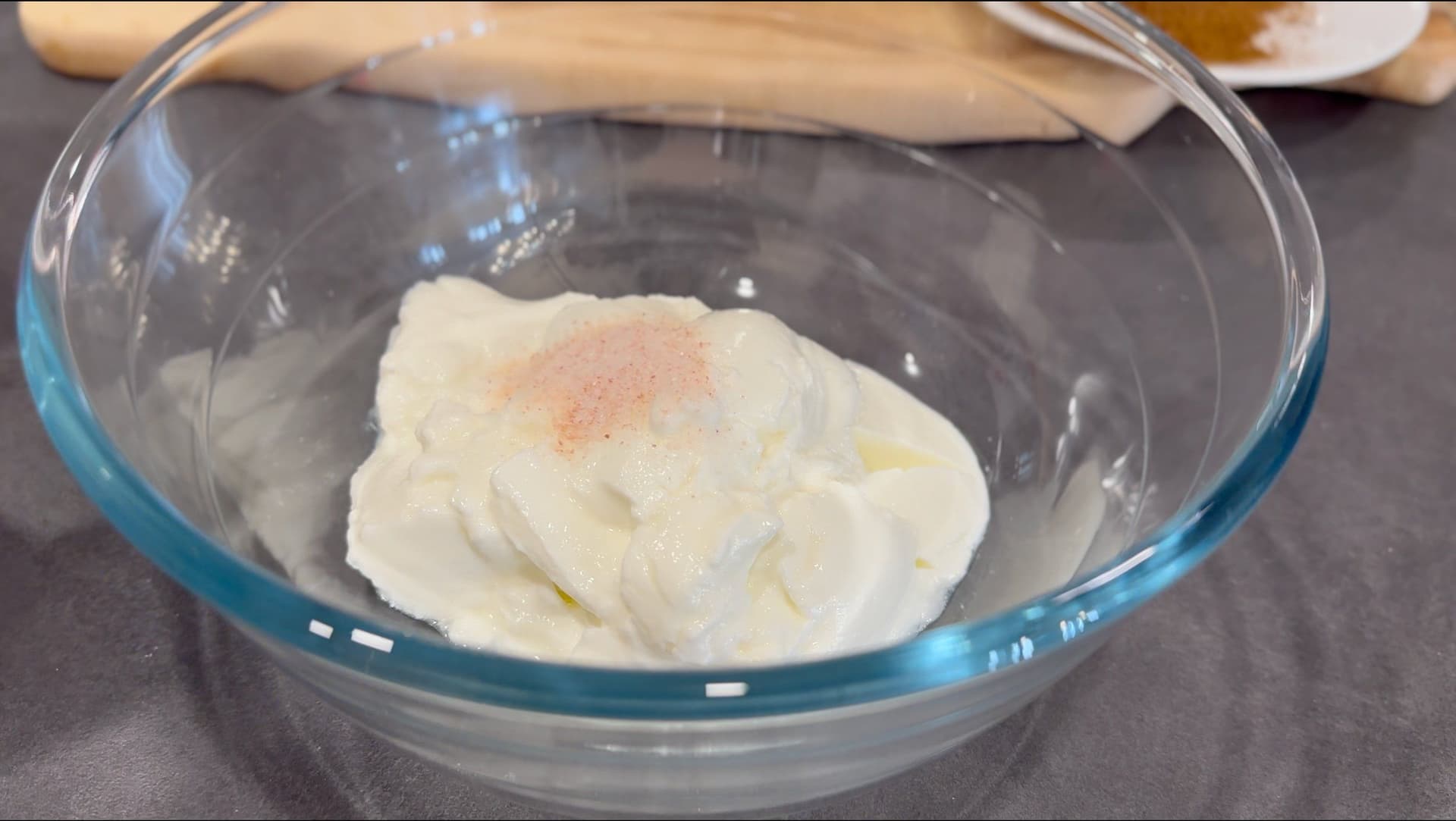 Yogurt with cumin powder and salt whisked together in a glass bowl, ready to be thinned with water.