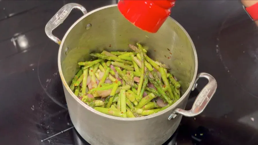 Chopped asparagus and red onions sautéed in a large pot with vegetable stock before blending.