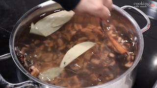 Simmering dal makhani in a pot with onion slices floating on top of the brown lentil mixture.