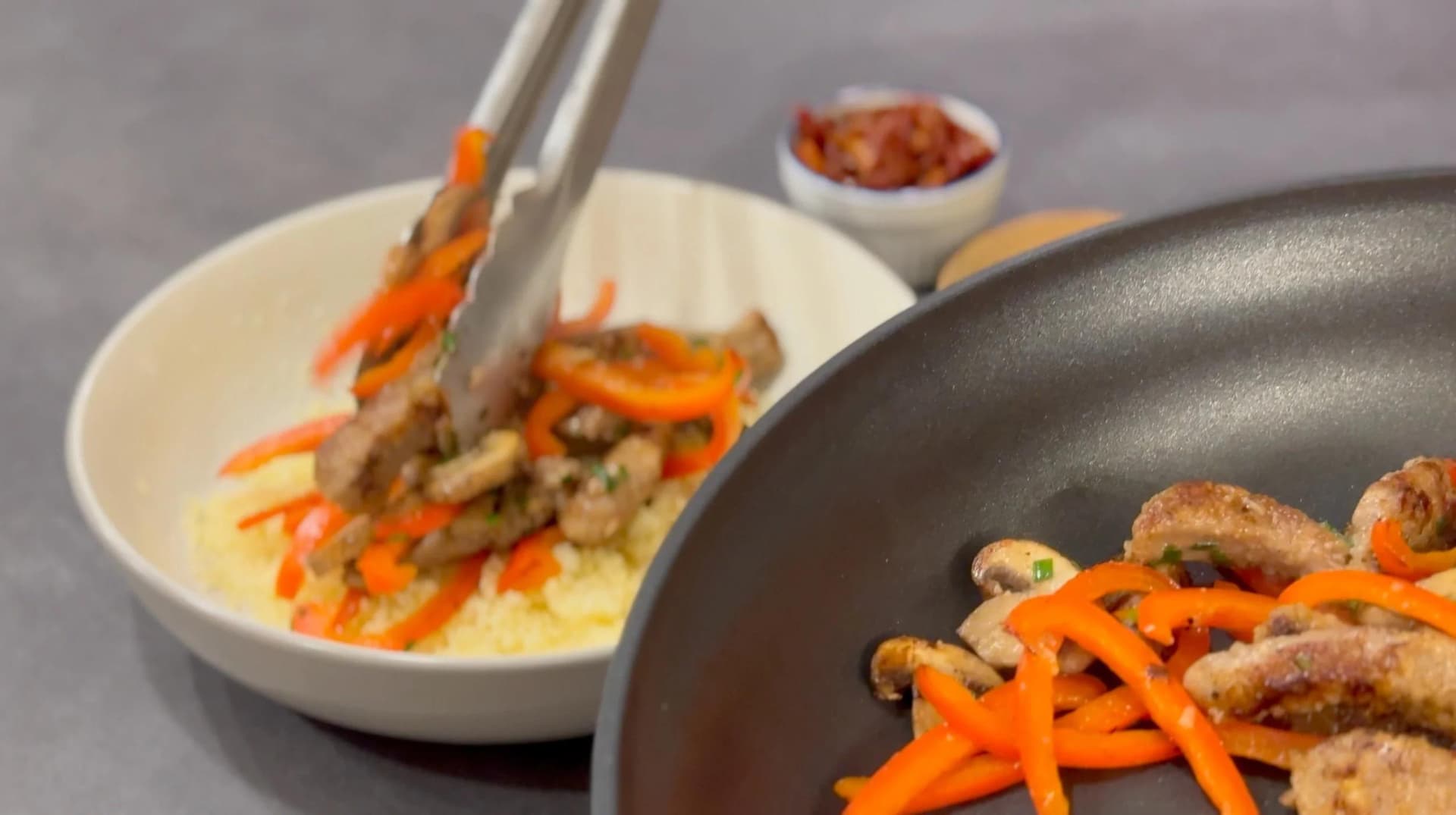Beef and vegetable couscous bowl being plated with sautéed beef strips and orange bell peppers.