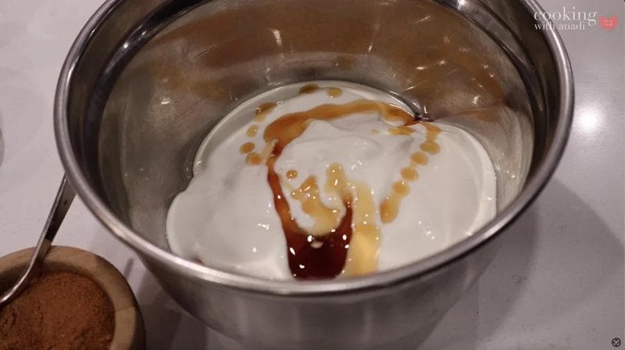 Pumpkin cream cheese filling whisked together in a stainless steel bowl with visible streaks of caramel and pumpkin puree.