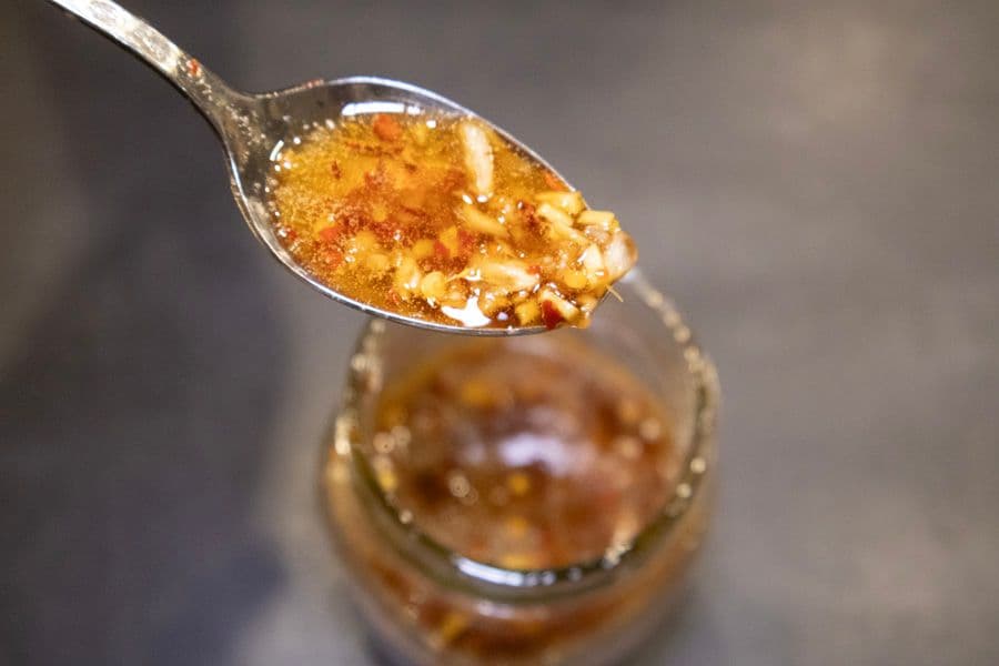 Golden stir fry sauce dripping from a spoon above a jar of the sauce.