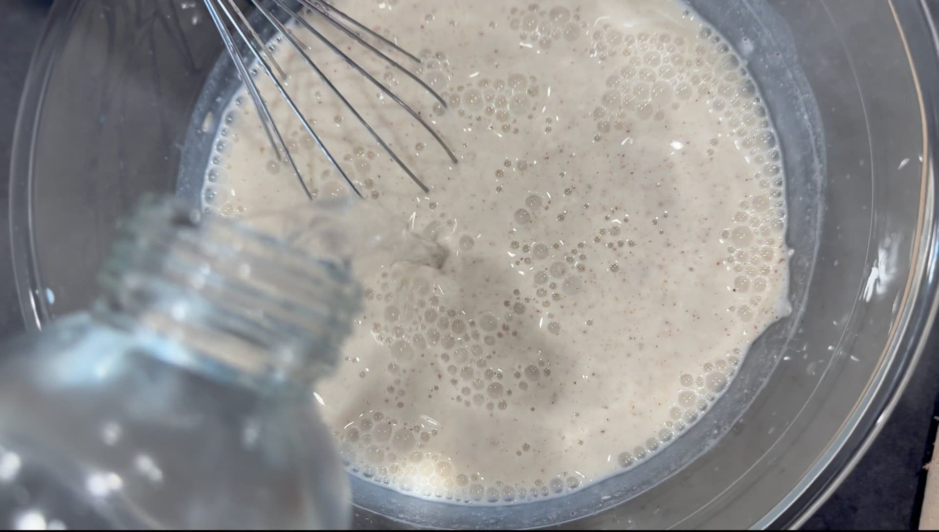 Whisking yogurt, salt, and cumin powder together in a bowl to make mattha, creating a foamy mixture.