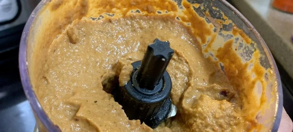 Spiced onion and ginger-garlic paste being blended into a smooth curry masala in a food processor.