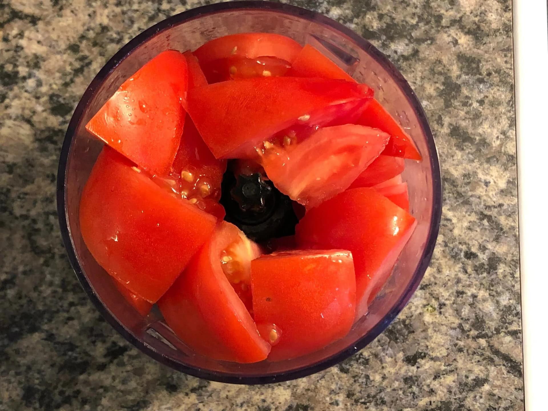 Red tomato pieces in a food processor with black blade, ready to blend into puree for masoor dal.