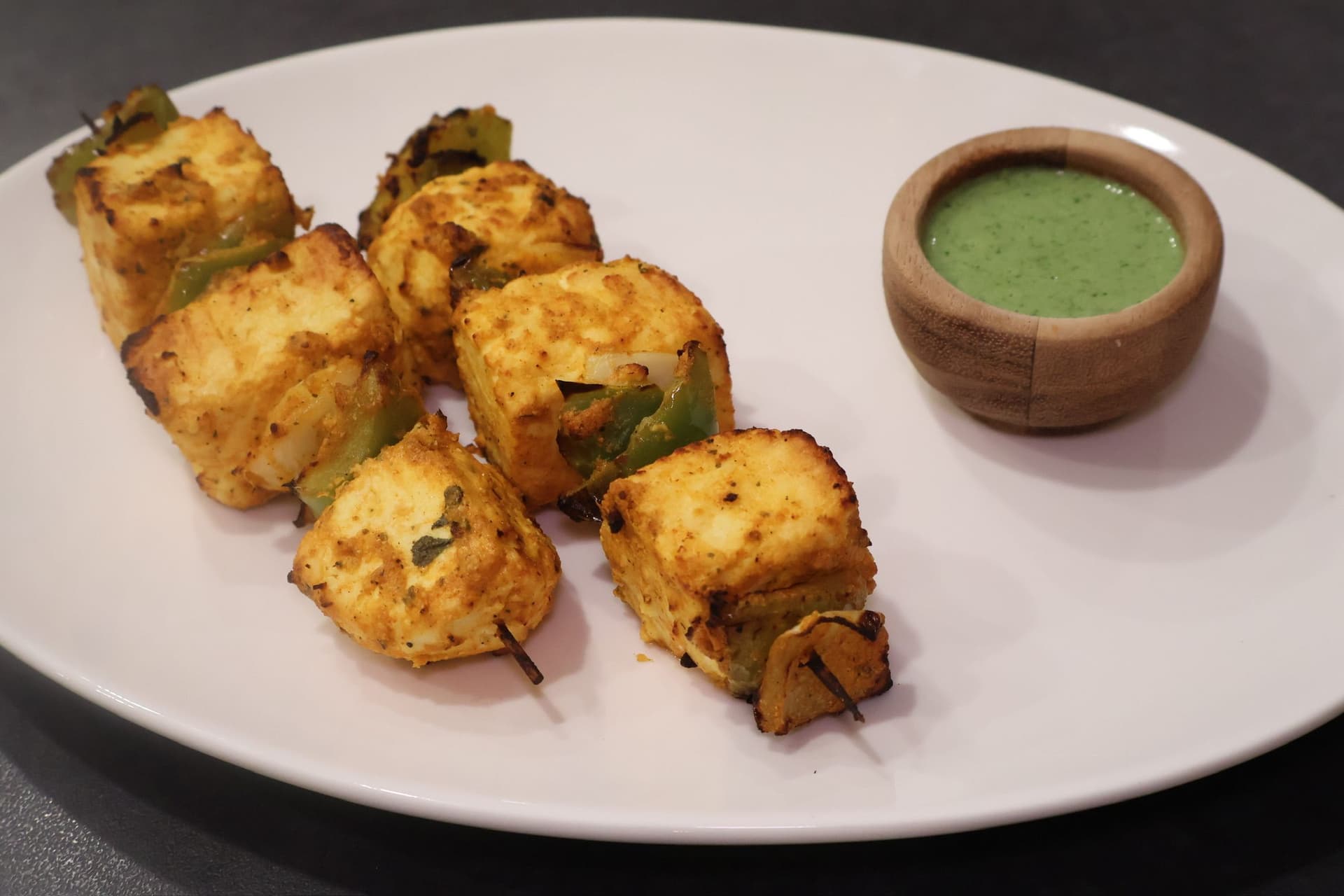 Cooked Air Fryer paneer tikka with a bowl of green mint chutney.