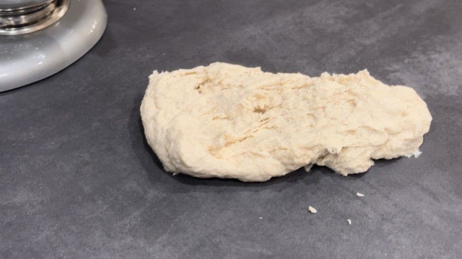 Pizza dough ball on dark countertop after kneading, ready for portioning and refrigeration.
