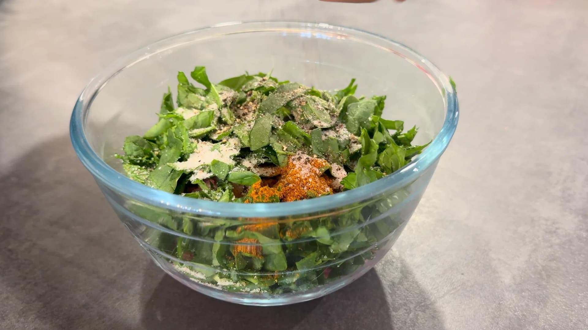 Ground turkey mixed with chopped spinach, garlic, and spices in a glass bowl before forming patties.