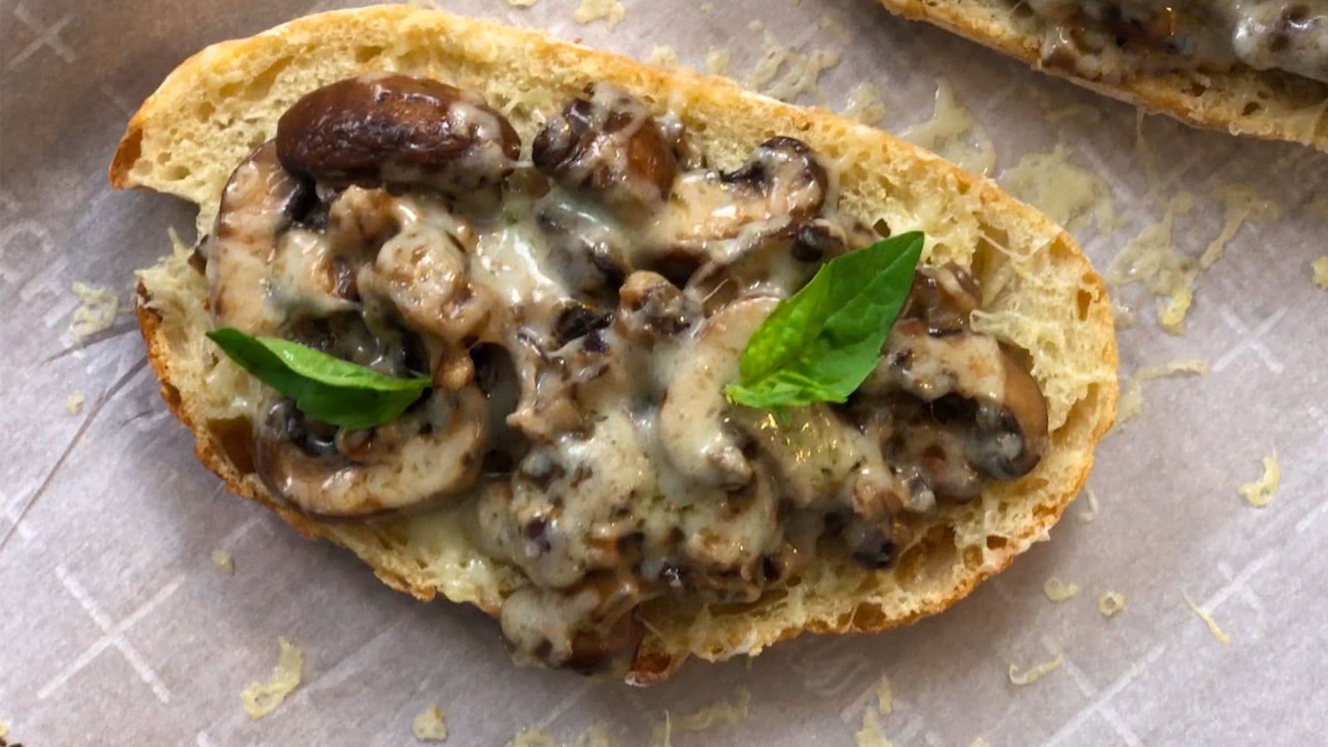 Toasted bread topped with sautéed mushrooms, melted cheese, and fresh basil leaves.