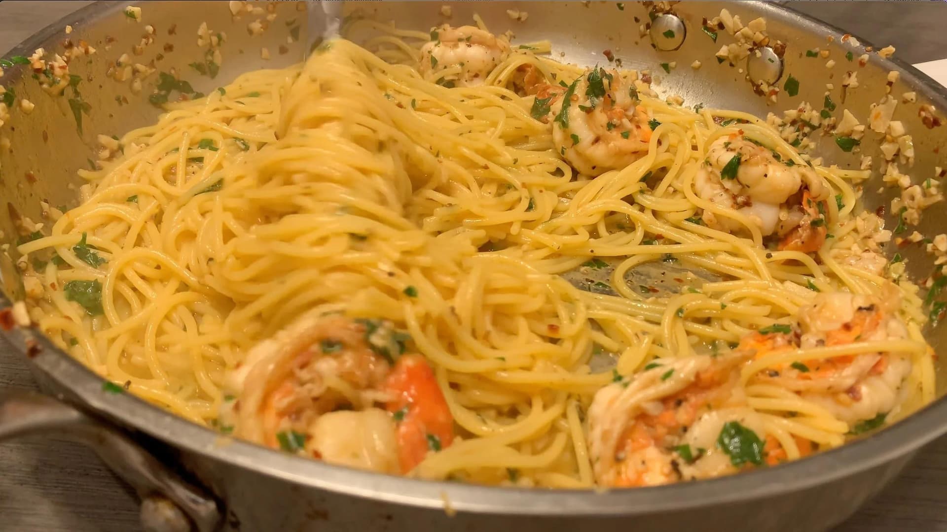 White wine lemon garlic shrimp scampi with spaghetti, garnished with parsley in a large pan.
