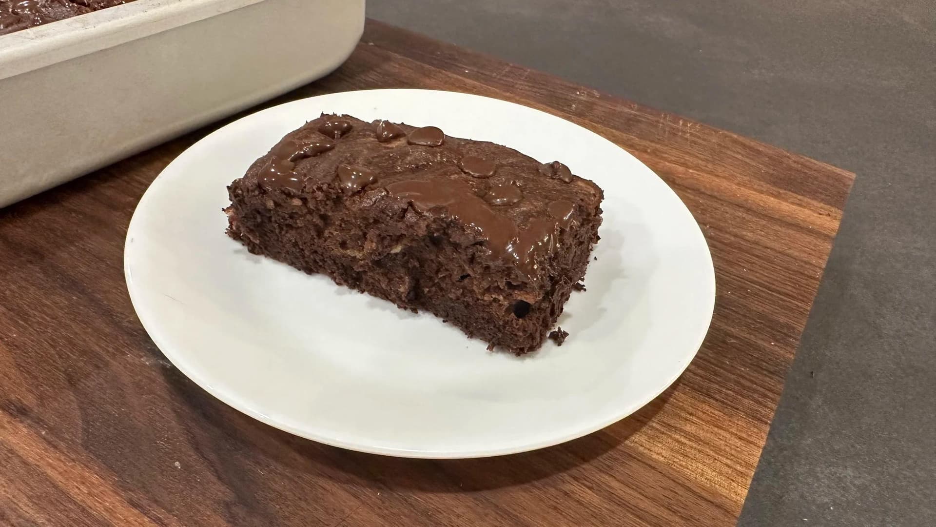 Slice of chocolate banana brownie with fudgy frosting on white plate