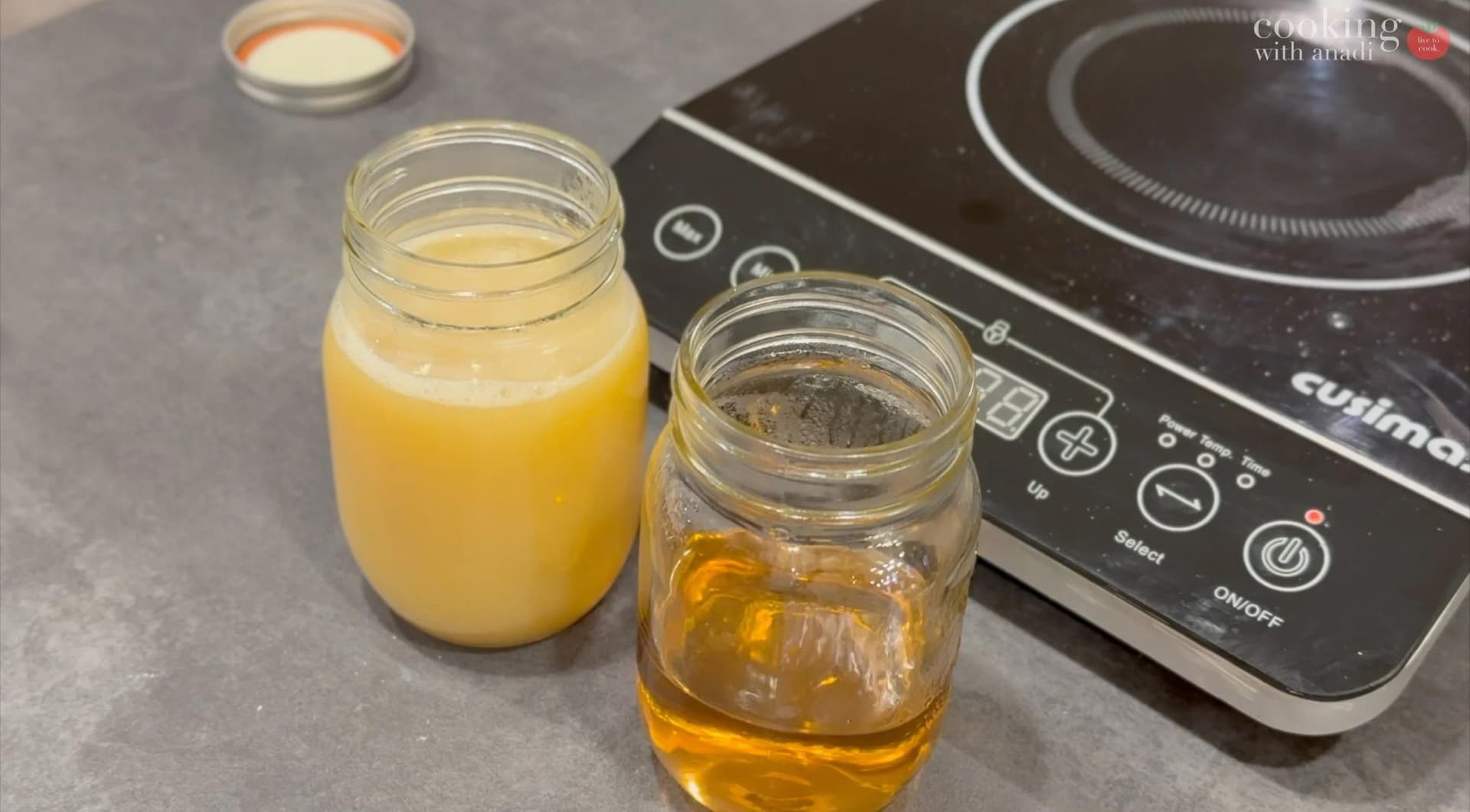 Cooled caramel sauce in a jar next to fresh orange juice, with an induction cooktop in the background.