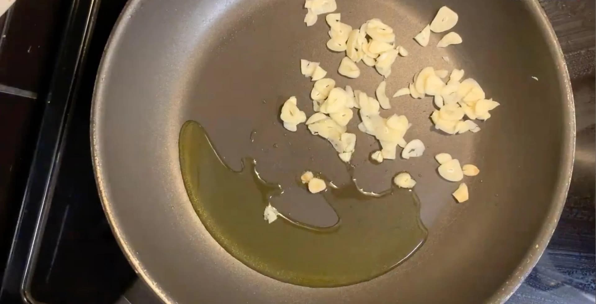 Minced garlic and red pepper paste sautéing in olive oil in a stainless steel pan.