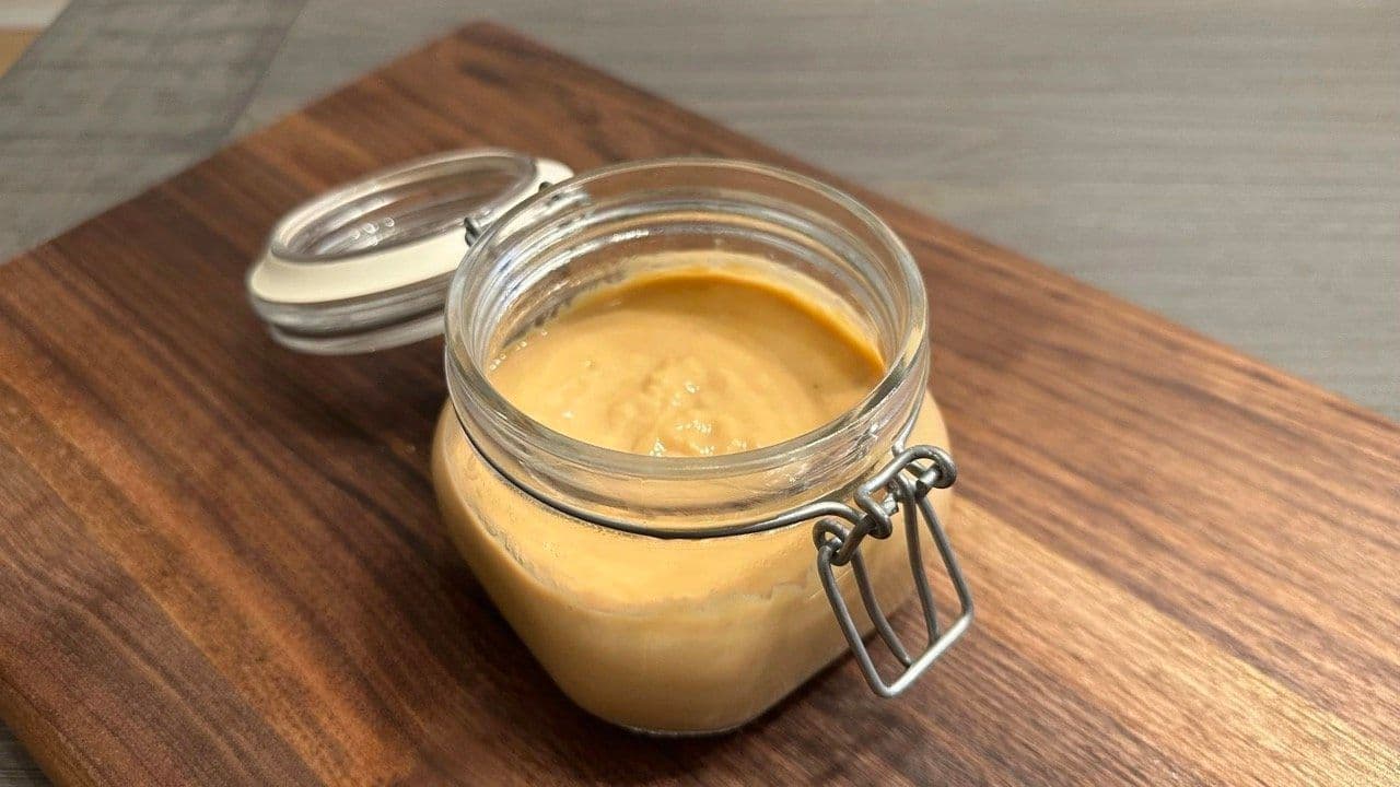Homemade lactose-free condensed milk in a glass jar with a wire-latch lid on a wooden board
