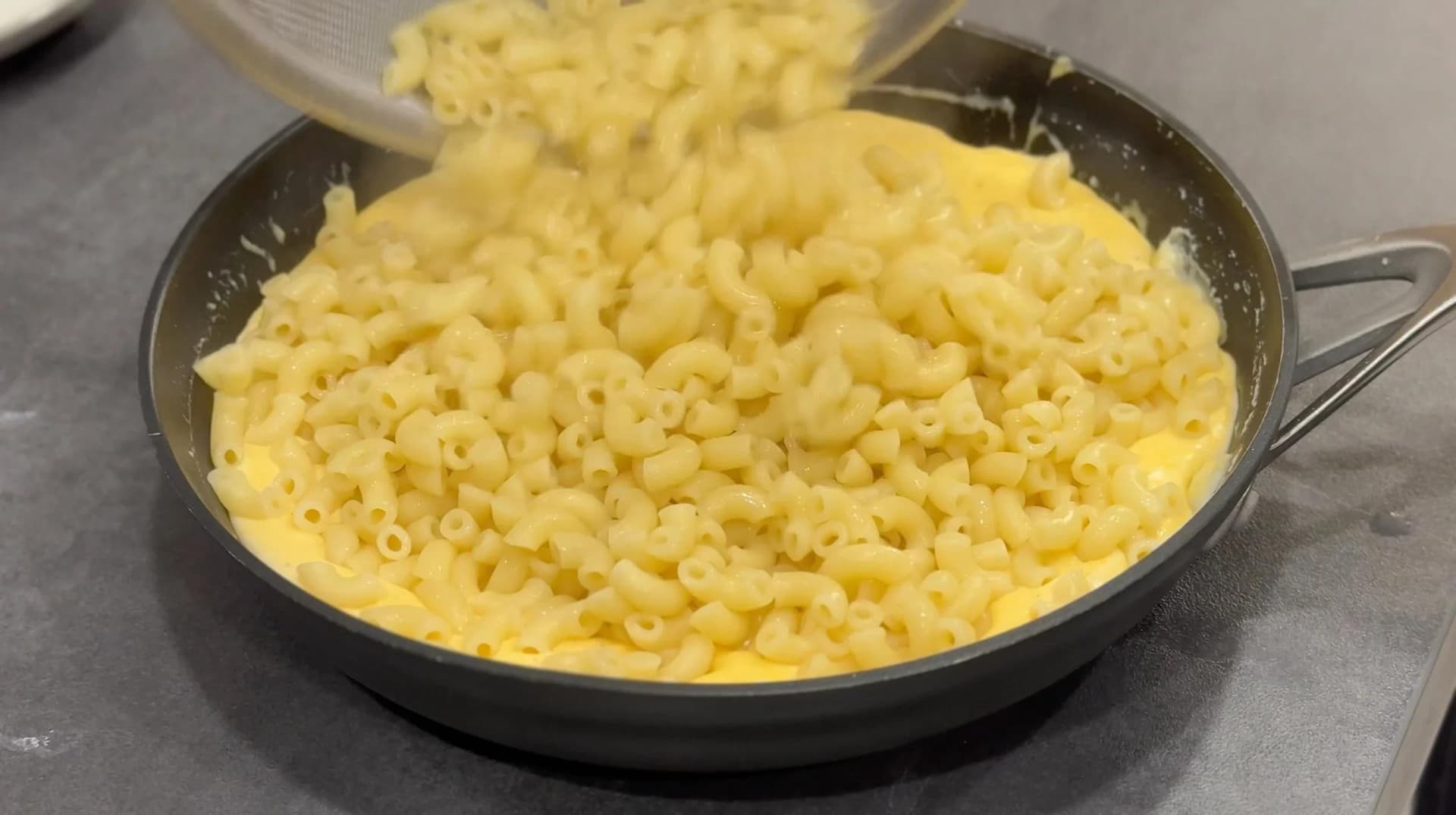 Creamy mac and cheese with elbow pasta and melted cheese sauce mixed with chives in a skillet.