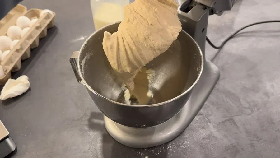 Stand mixer with dough hook mixing soft dinner roll dough in stainless steel bowl