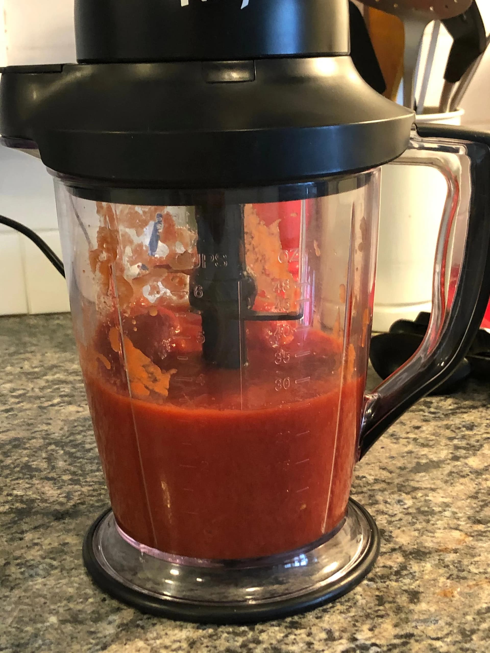 Pulsed San Marzano tomatoes in a food processor jug, showing chunky red tomato mixture.