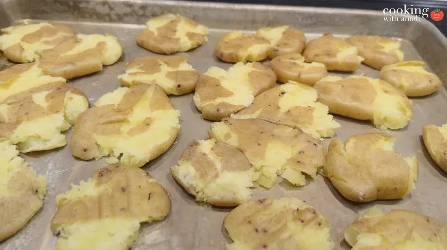 Smashed fingerling potatoes on parchment paper, brushed with butter and oil, ready for air frying.