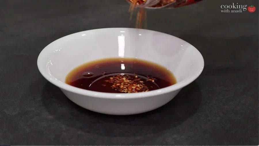 Dark soy sauce mixture with sesame oil and red chili flakes in a white bowl, ready for egg roll in a bowl recipe.