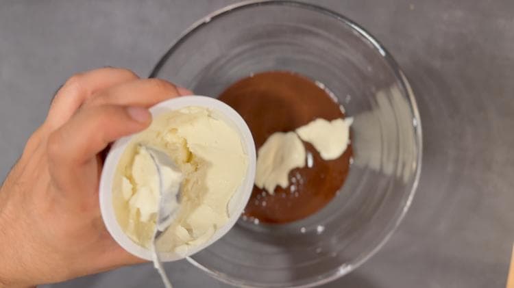 Cream cheese being added to melted Nutella in a glass bowl during pie filling preparation.