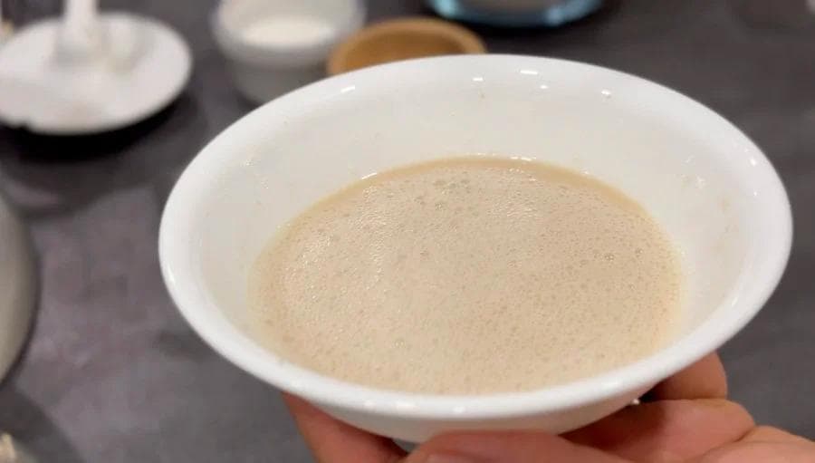 Yeast mixture with bubbles whisked in a white bowl, ready to be added to dry ingredients.
