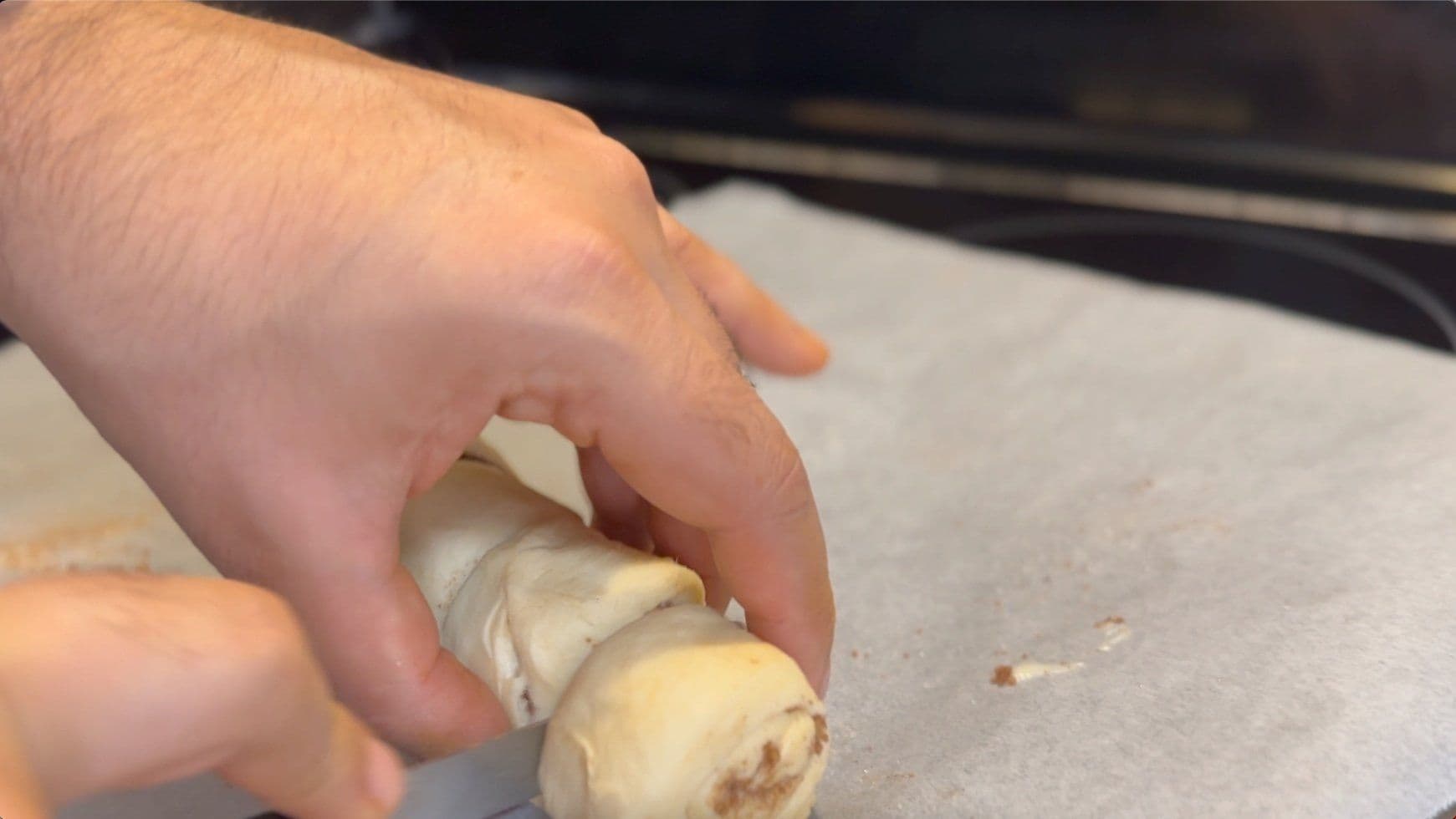 Hand rolling crescent dough with cinnamon sugar filling into a tight spiral for baby cinnamon rolls.