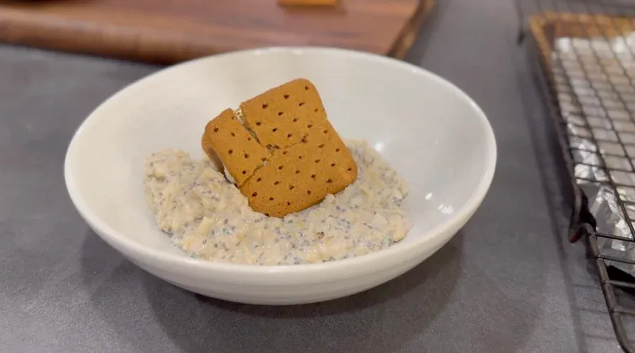 White bowl of oatmeal topped with two square crackers and chocolate chips.