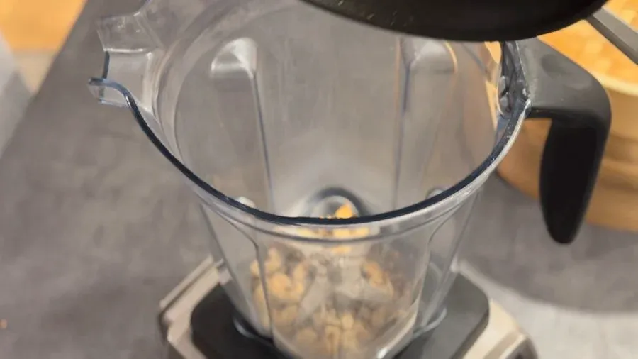 Blender filled with roasted cashews, seeds, tomatoes, and red chillies ready to blend into chutney.