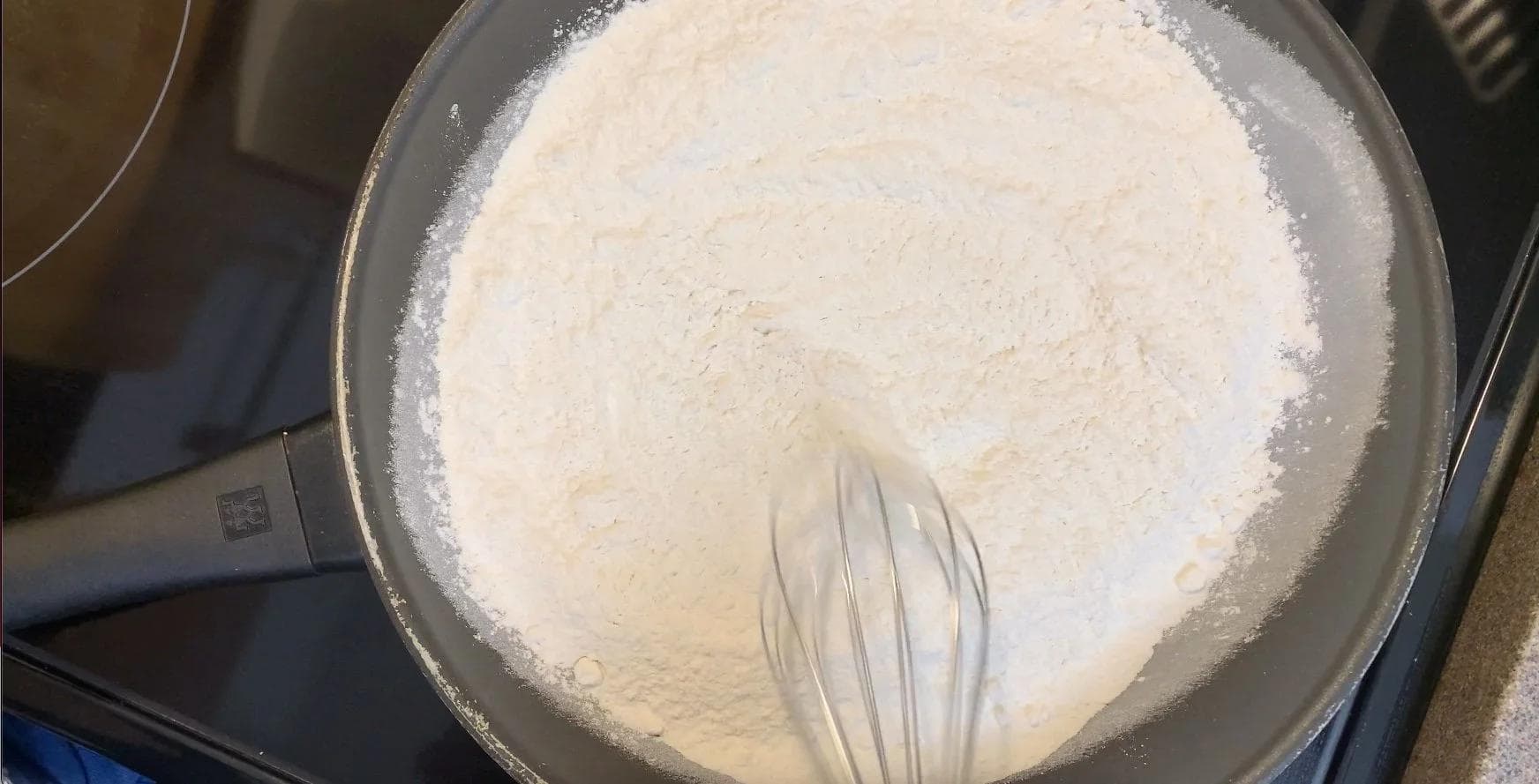 Roasted flour cooling in a saucepan with a whisk, ready for edible cookie dough.