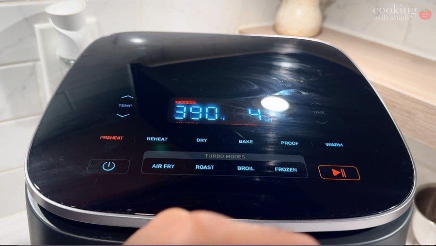 Air fryer displaying 390°F preheat temperature on digital screen with turbo modes visible.