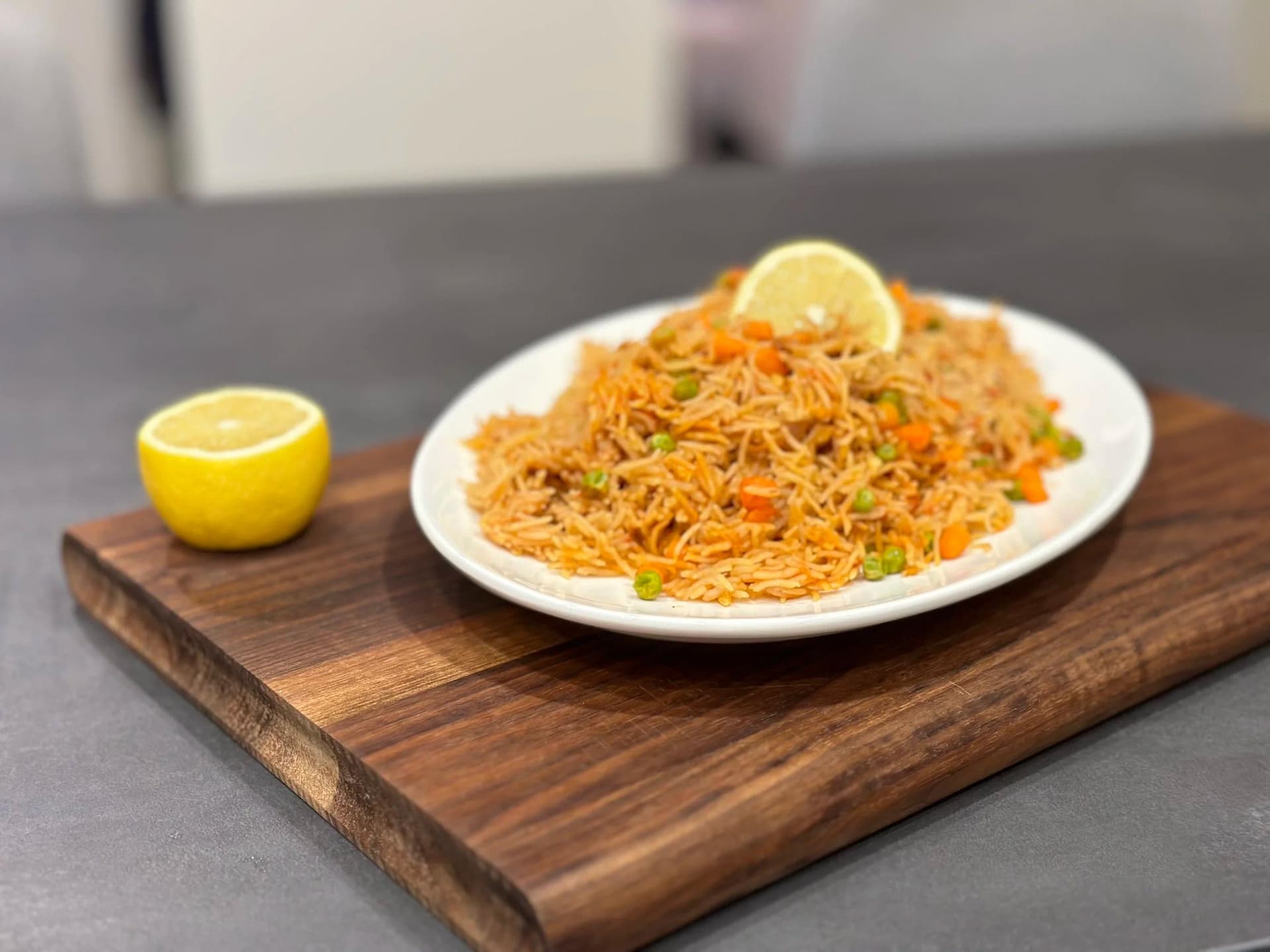 Golden crispy chow mein noodles on white plate with lemon slice, served on wooden board with lemon half