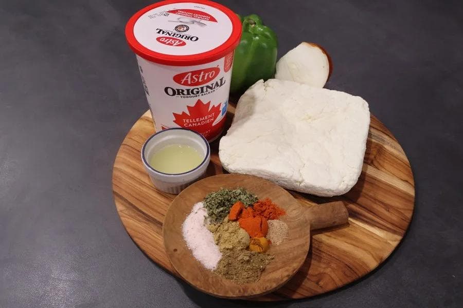 Ingredients for air fryer paneer tikka laid out on a wooden board: paneer, yogurt, green pepper, ghee, and spice mix.