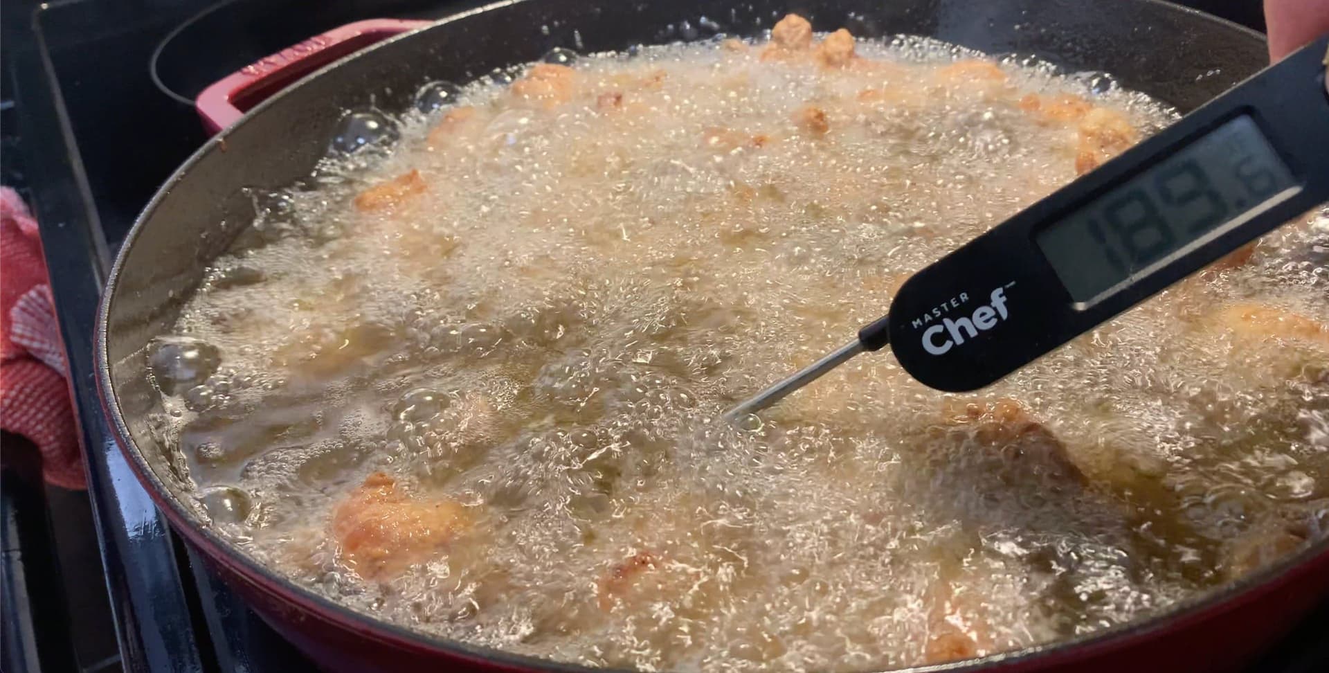 Chicken pieces frying in golden oil at 320-350F in a red pot, with a thermometer measuring the temperature.