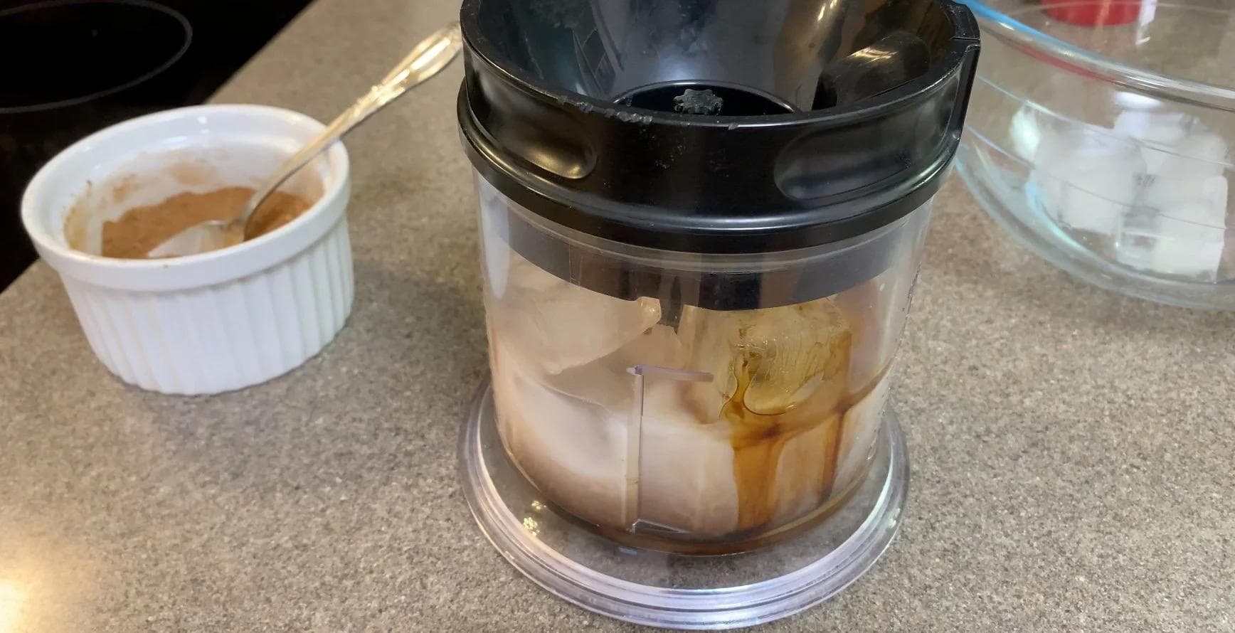Blender filled with crushed ice and tan-colored pumpkin spice frappuccino mixture during blending process.