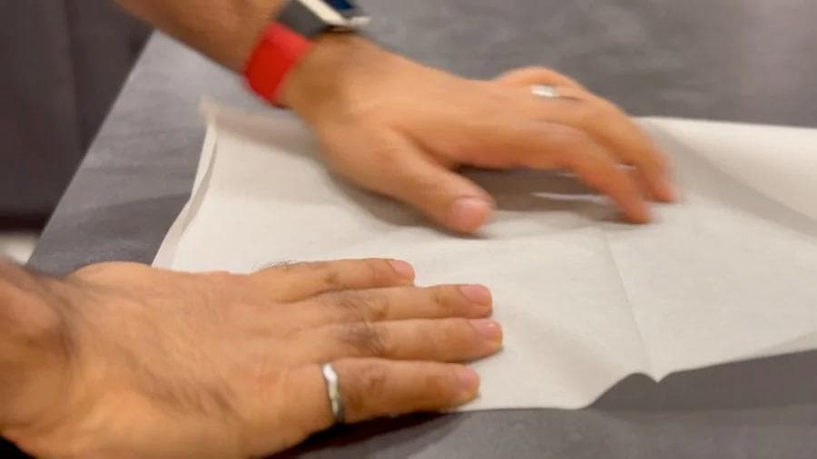 Hands wrapping a breakfast burrito in parchment paper for freezing and storage.