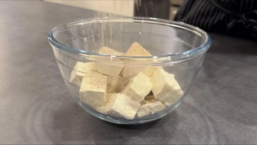 Cubed tofu in a glass bowl ready to be mixed with seasonings and cornstarch.