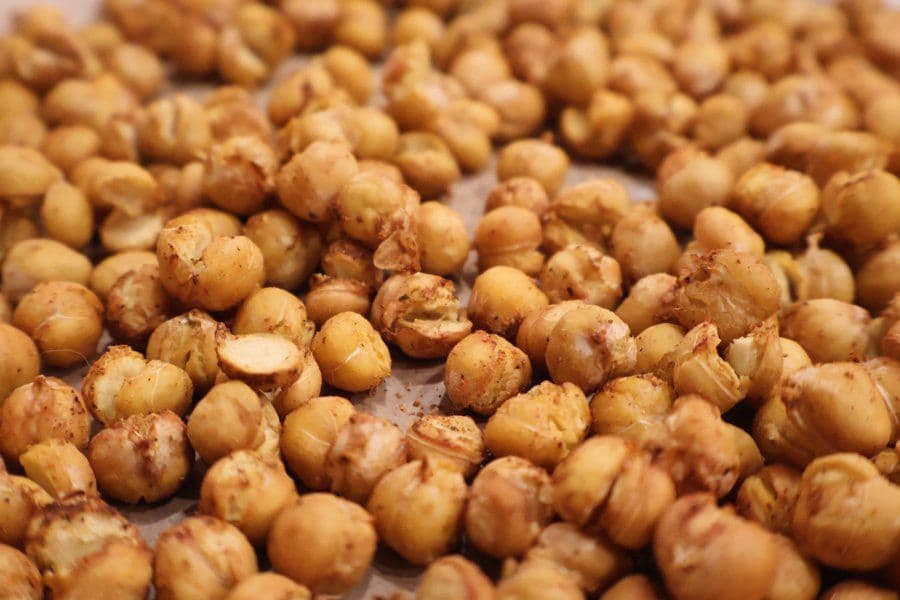 Crispy roasted chickpeas with golden-brown coating and seasoning scattered on parchment paper.