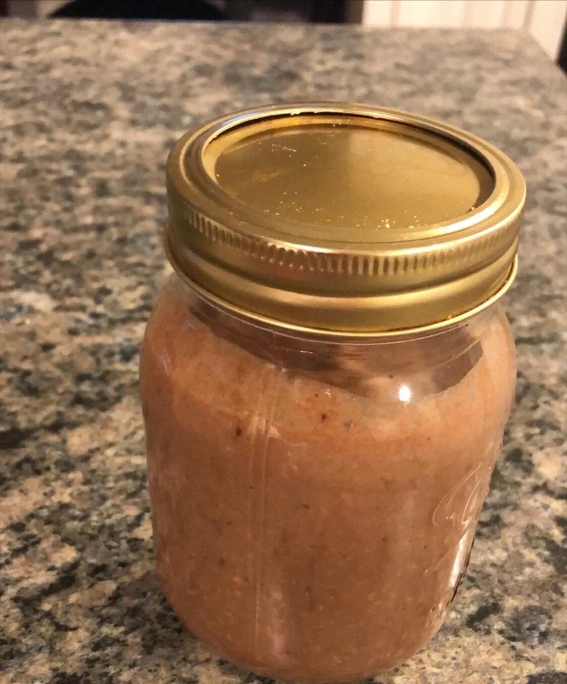 Mason jar of chocolate banana strawberry overnight oats with gold lid on granite countertop.